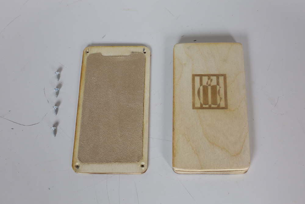 a wooden phone case bottom and lid with four screws lined up next to them